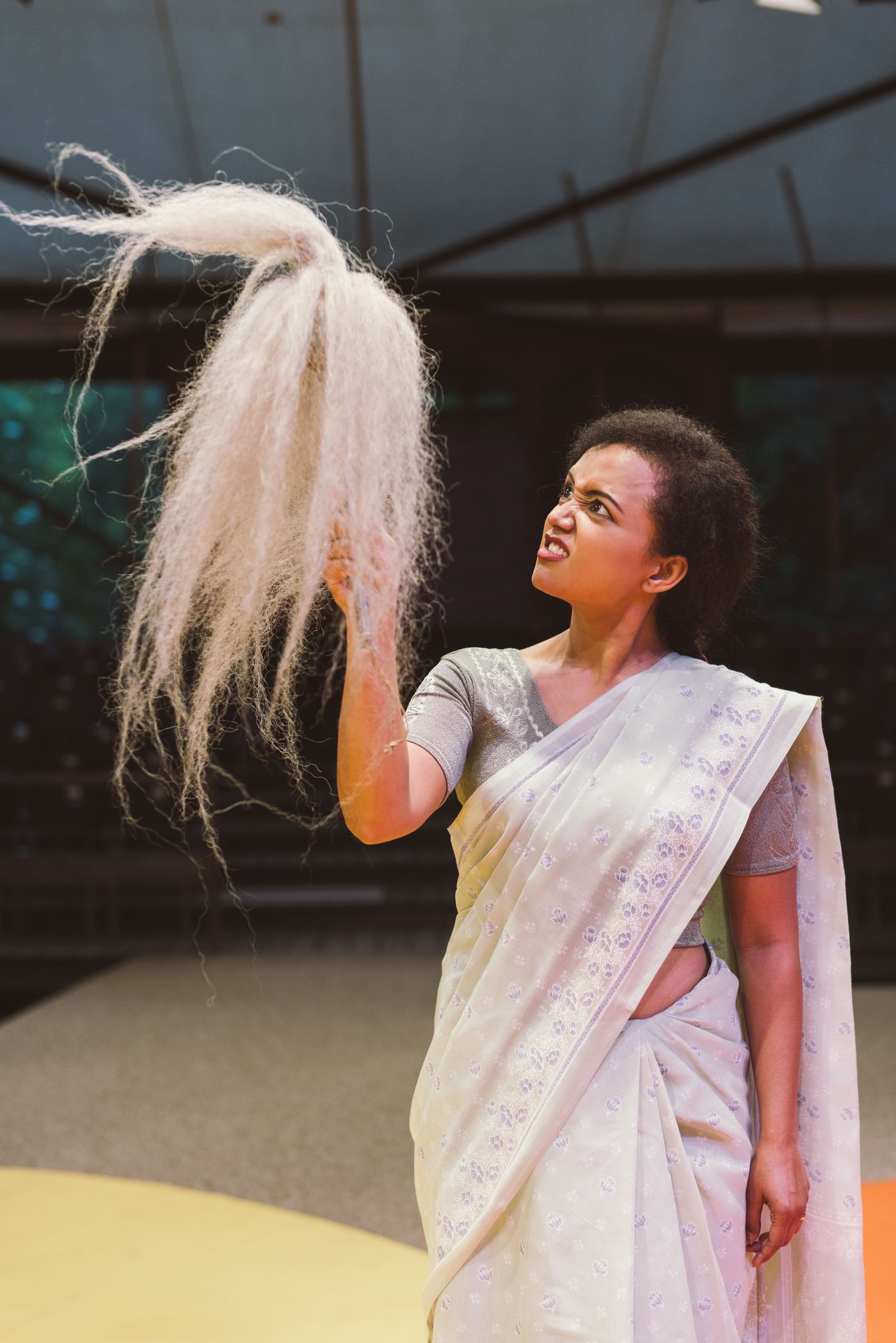 Pranali performing in a white sari while holding a large fibre-like prop.