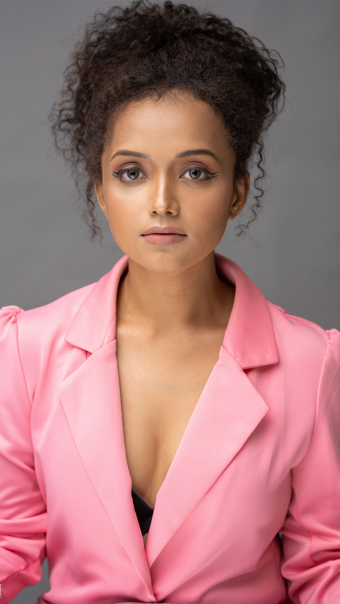 Pranali in a pink blazer facing the camera against a grey background.