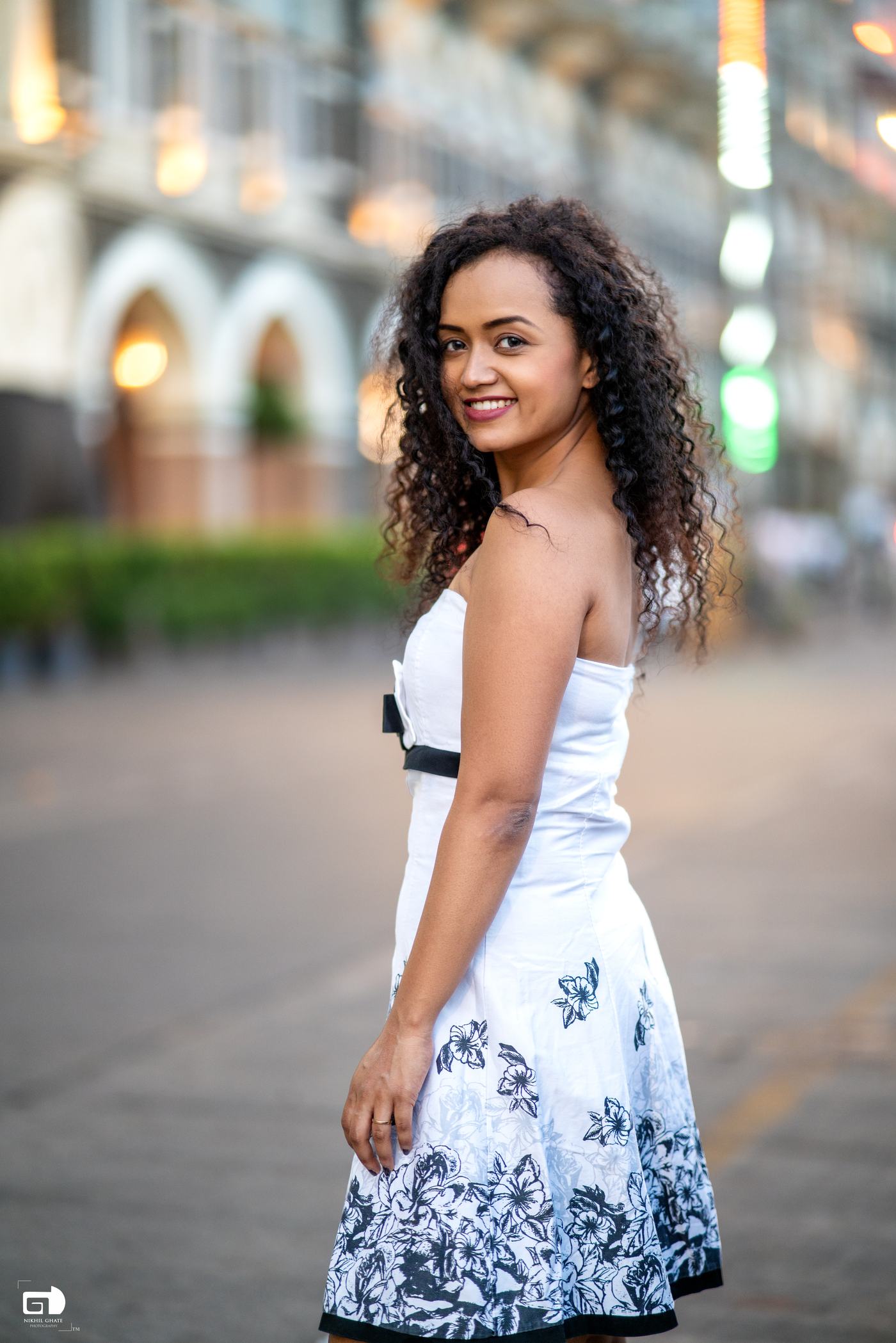 Pranali smiling outdoors in a white dress.