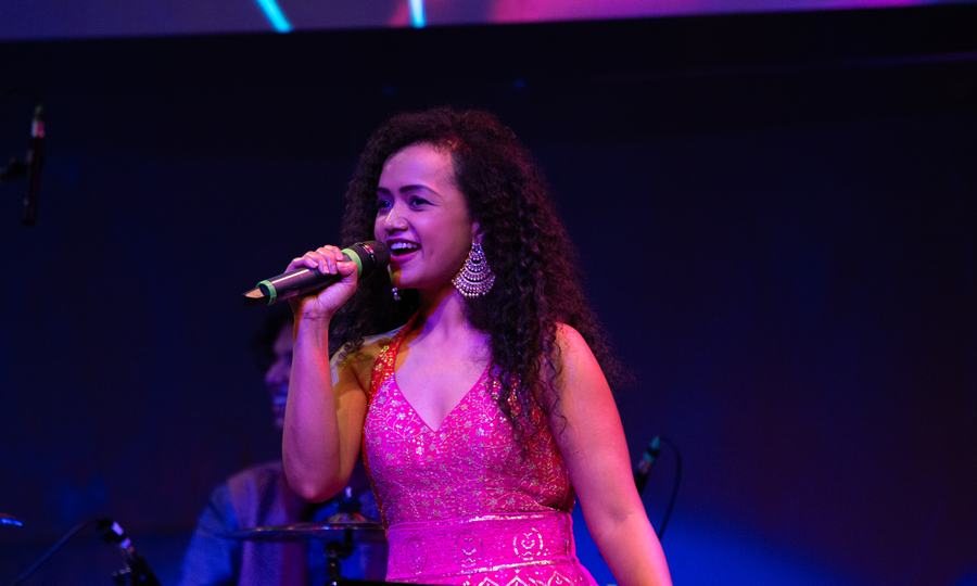 Pranali singing into a microphone at an evening event.
